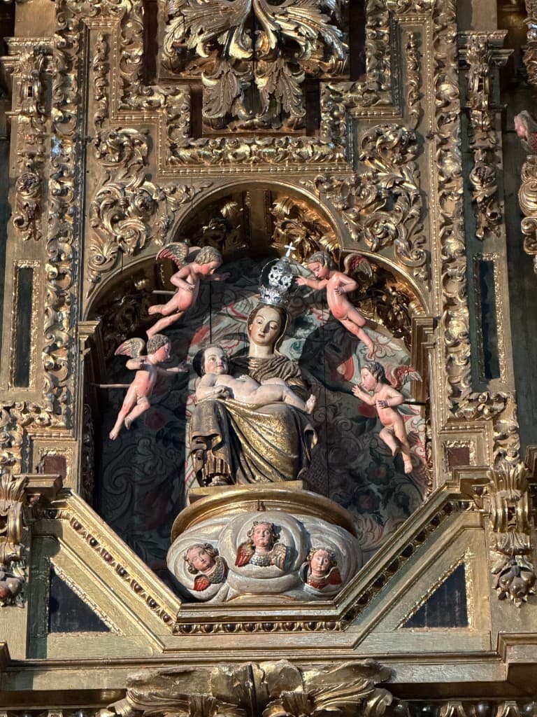 An ornate gilded Catholic altarpiece with sacred figures and carved gold detail.